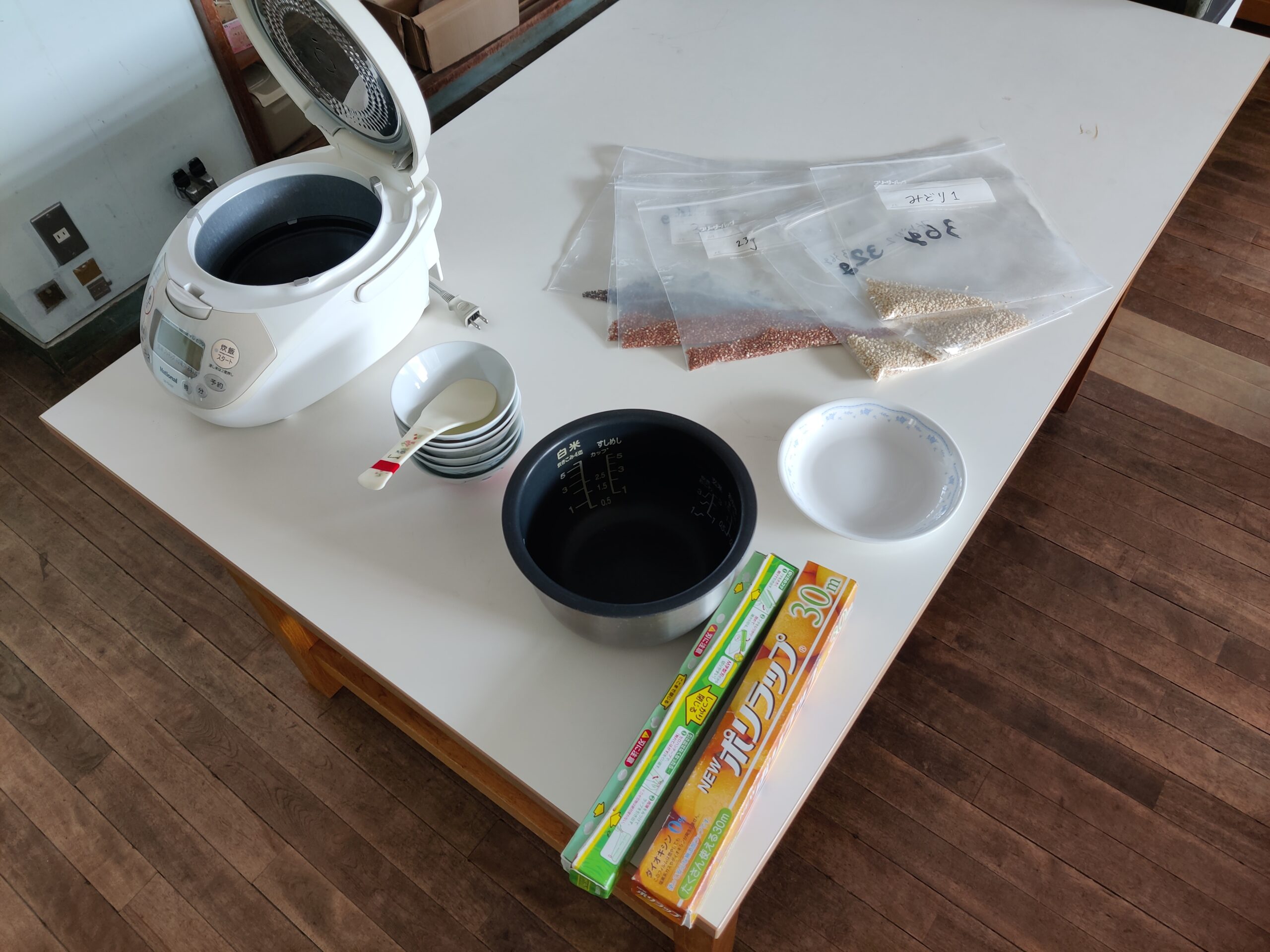 Table with rice cooker, bowels, clingfilm and zip-lock bags with Red, Black and white ancient rice.